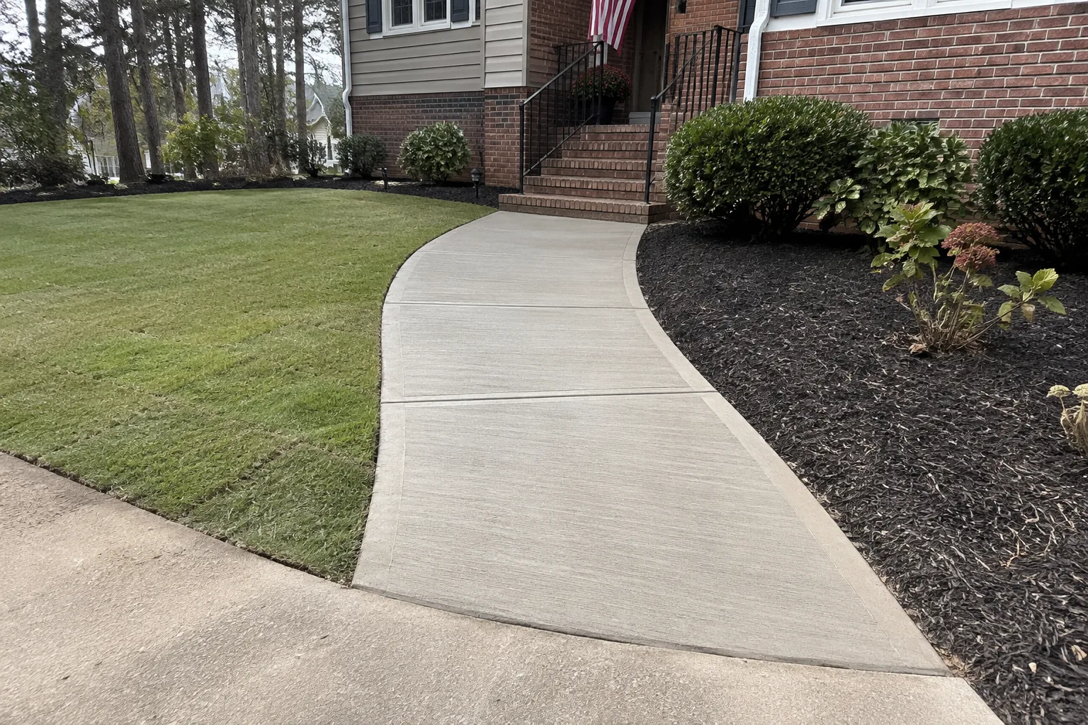 Finished broom-finish concrete walkway with fully restored lawn and mulch transitions