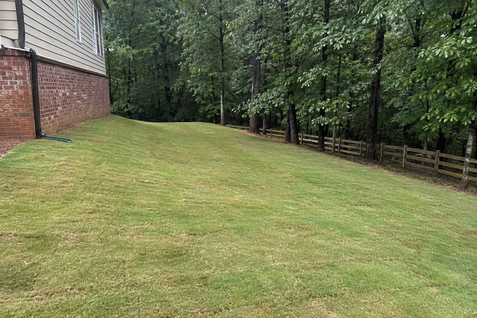 Finished grassed swale carrying water away from a house