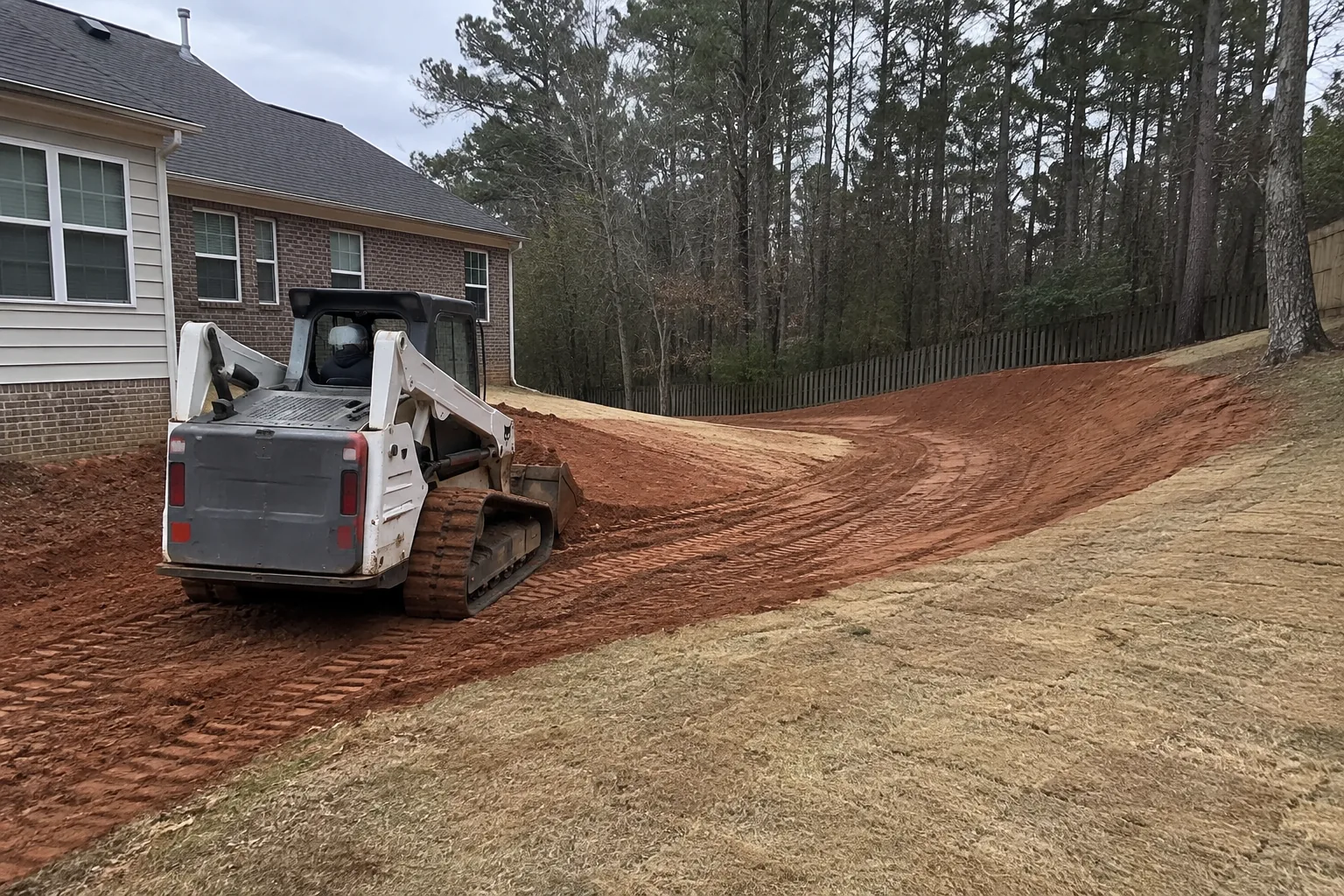 Compact track loader shaping a shallow drainage swale